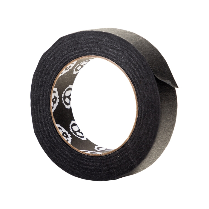 Un rouleau de Ruban adhésif microporeux Killer Ink (3 cm x 50 m) avec une finition noire et un bord partiellement décollé révélant la face collante. L'intérieur du carton est orné d'un motif de crâne blanc répétitif. Le tout sur un fond blanc uni.